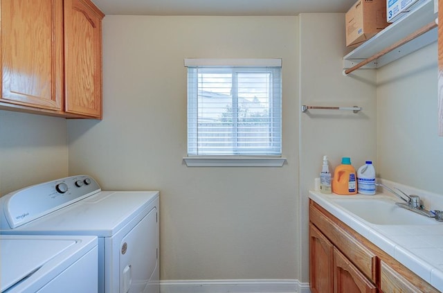 clothes washing area with cabinets, washer and dryer, and sink