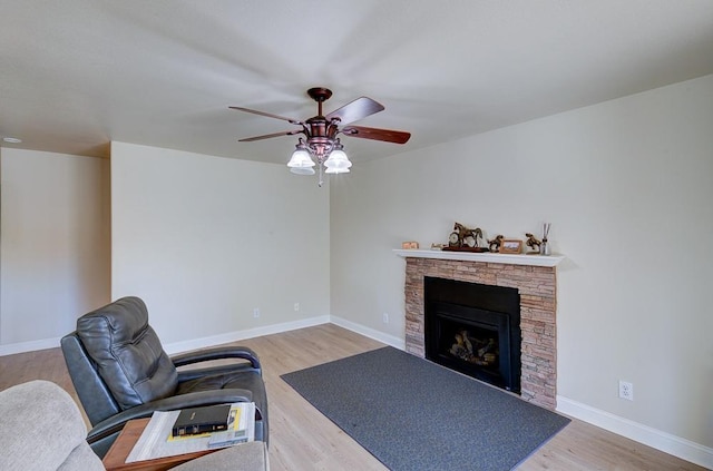 living room featuring a fireplace, wood-type flooring, and ceiling fan