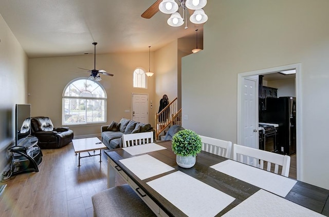 dining area with hardwood / wood-style floors, high vaulted ceiling, and ceiling fan