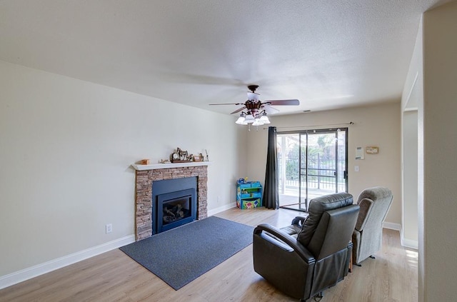 1147 N Carey Ave, Clovis, CA 93611 - living room with light wood-style floors, a stone fireplace, a ceiling fan, and baseboards