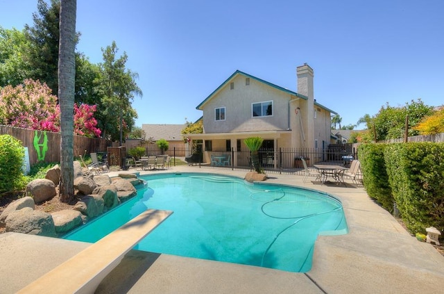 view of swimming pool featuring a diving board and a patio area