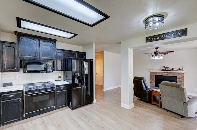 kitchen featuring ceiling fan, tile counters, black appliances, light hardwood / wood-style floors, and decorative backsplash