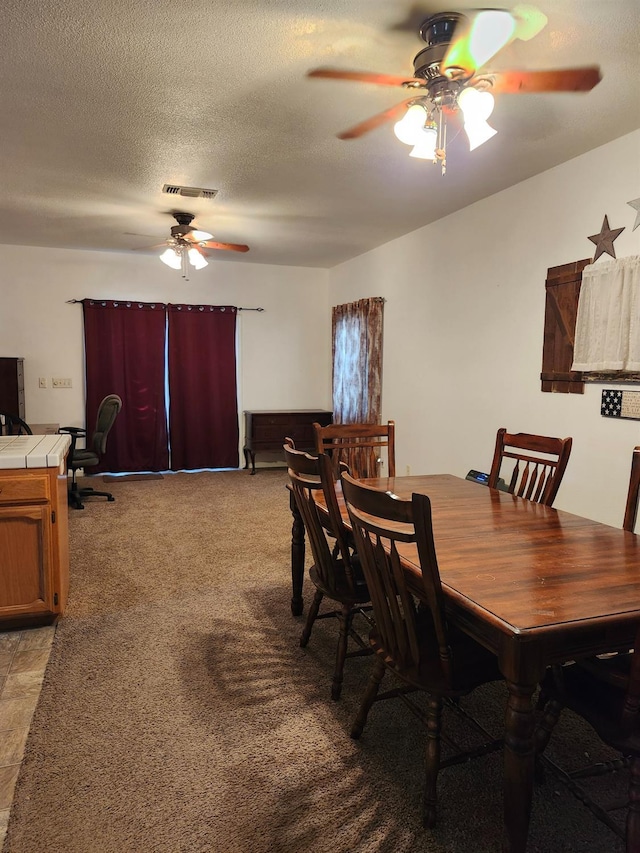 carpeted dining room with ceiling fan and a textured ceiling