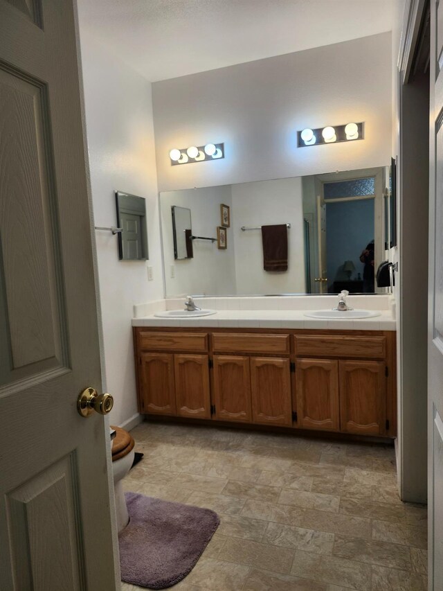 bathroom with double vanity, stone finish floor, a sink, and toilet