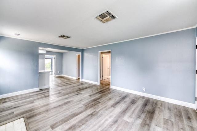 empty room featuring ornamental molding and light hardwood / wood-style floors