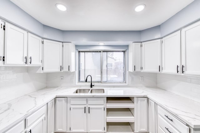 kitchen with white cabinetry, sink, backsplash, and light stone counters