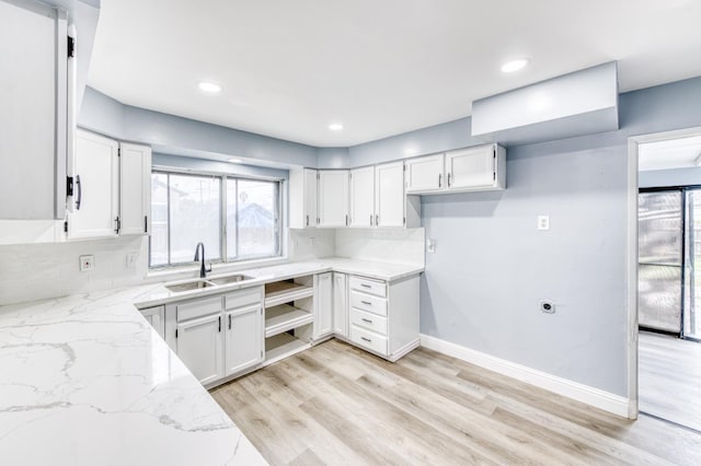 kitchen featuring white cabinetry, light stone countertops, sink, and a wealth of natural light