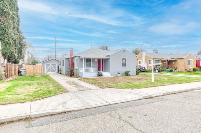 single story home featuring a porch, a front yard, and a storage shed