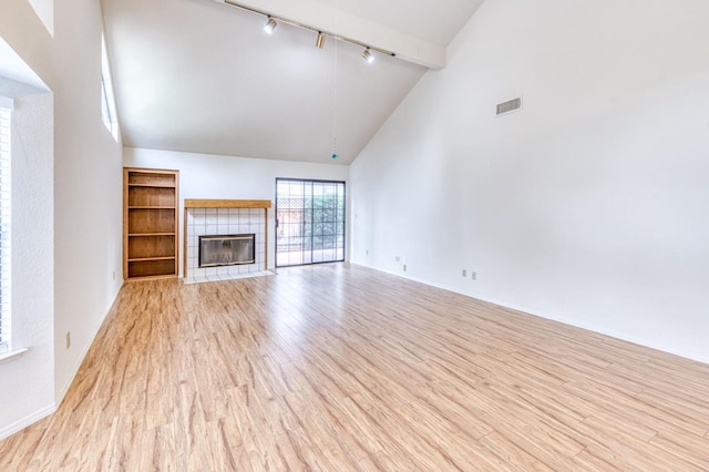 unfurnished living room with light hardwood / wood-style flooring, high vaulted ceiling, a fireplace, track lighting, and beamed ceiling