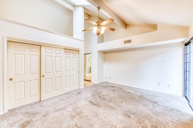 unfurnished bedroom with ceiling fan, high vaulted ceiling, light carpet, a closet, and beamed ceiling