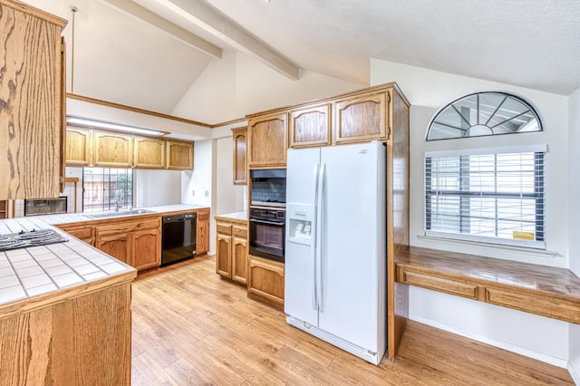 kitchen featuring vaulted ceiling with beams, black appliances, tile countertops, kitchen peninsula, and light wood-type flooring