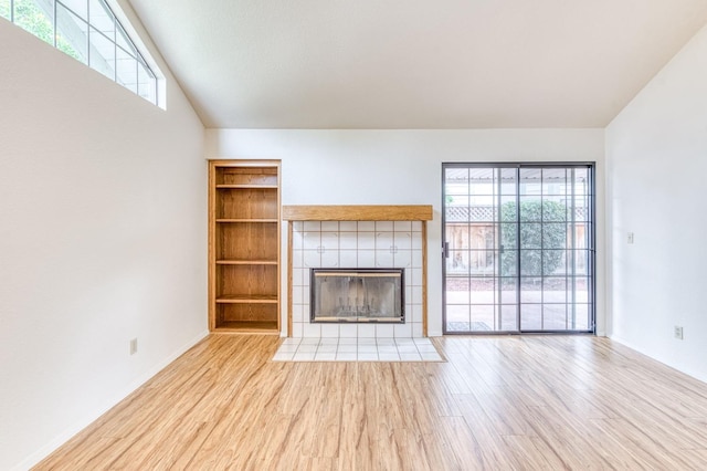 unfurnished living room with lofted ceiling, a fireplace, and light wood-type flooring