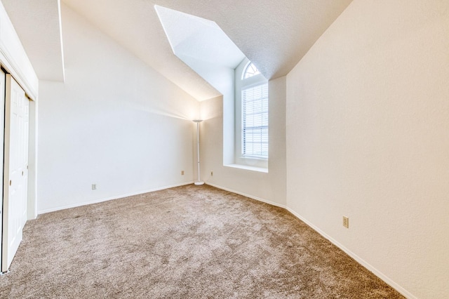 bonus room featuring lofted ceiling, a textured ceiling, and carpet flooring