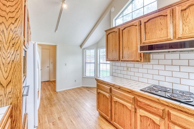 kitchen featuring light hardwood / wood-style flooring, backsplash, electric cooktop, tile countertops, and white fridge