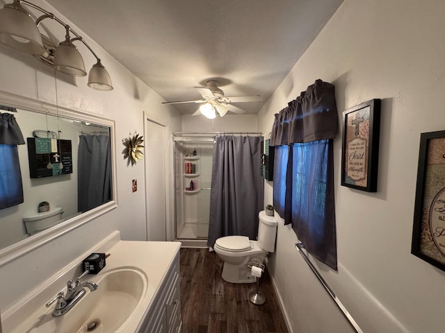 bathroom with walk in shower, toilet, vanity, ceiling fan, and hardwood / wood-style floors