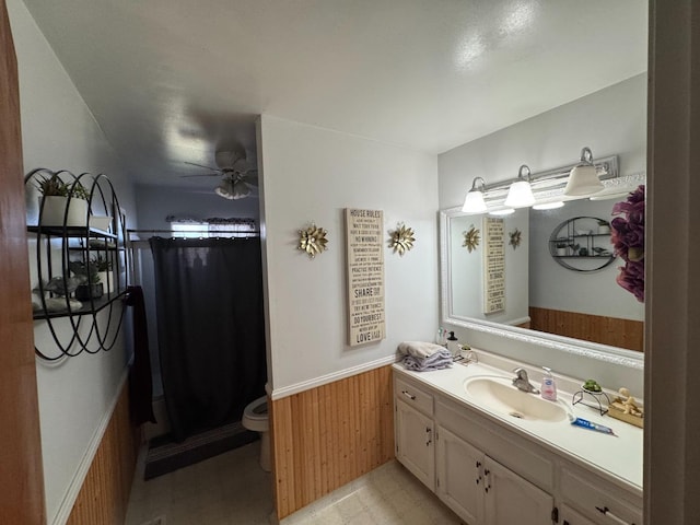 bathroom with ceiling fan, wooden walls, vanity, a shower with curtain, and toilet