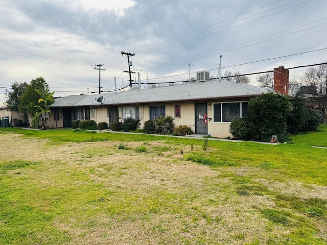 ranch-style home featuring cooling unit and a front lawn