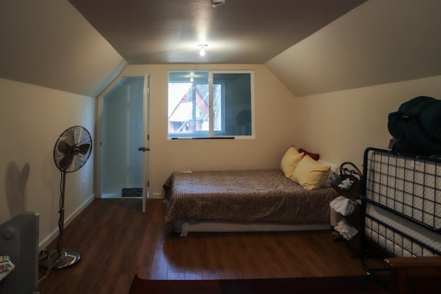 bedroom with dark hardwood / wood-style flooring, radiator, and vaulted ceiling