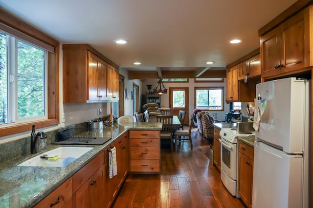 kitchen featuring sink, white appliances, dark wood-type flooring, light stone counters, and kitchen peninsula