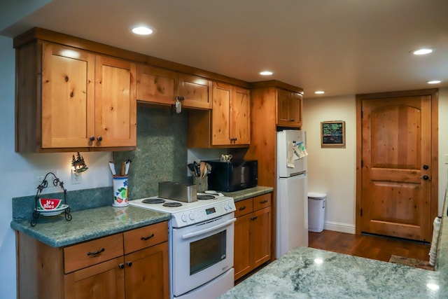 kitchen with dark hardwood / wood-style floors, light stone counters, and white appliances