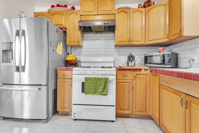 kitchen with backsplash, tile countertops, range hood, appliances with stainless steel finishes, and marble finish floor