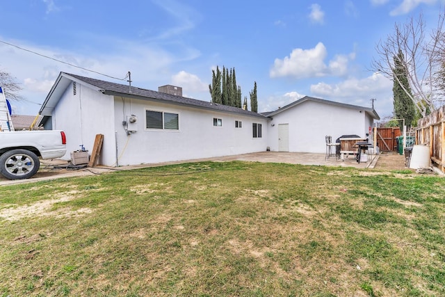 rear view of property with a patio, a yard, fence, and stucco siding