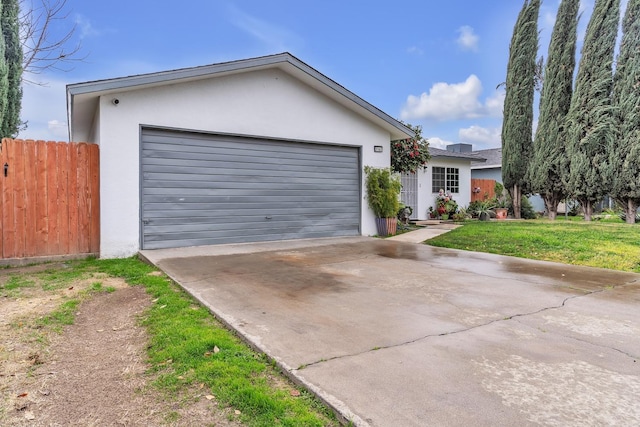 view of front of house with a front yard, fence, an attached garage, stucco siding, and concrete driveway