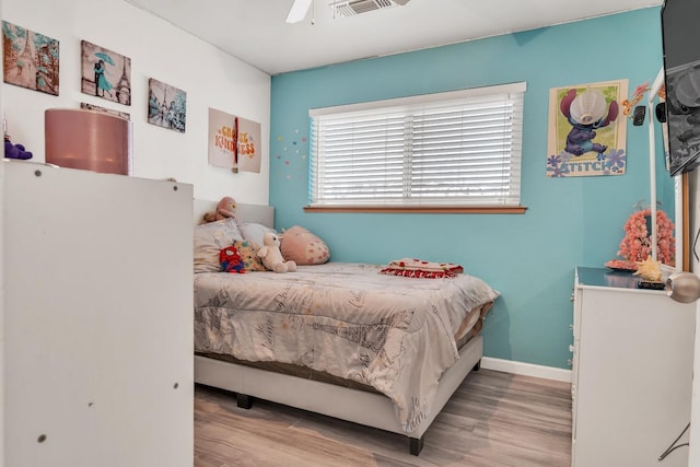 bedroom with visible vents, a ceiling fan, baseboards, and wood finished floors