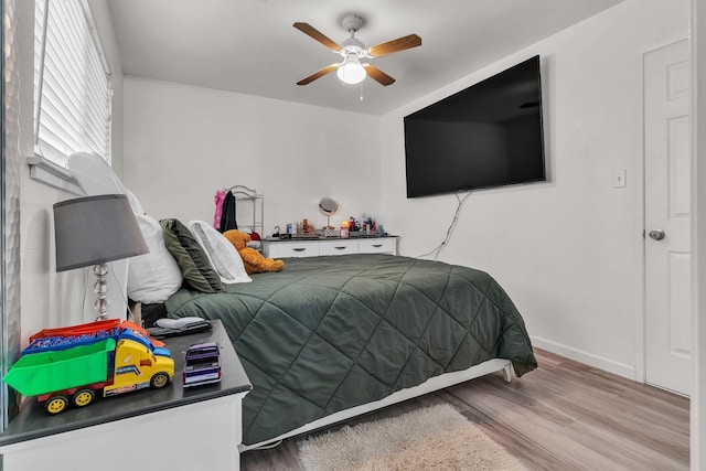 bedroom featuring baseboards, wood finished floors, and a ceiling fan