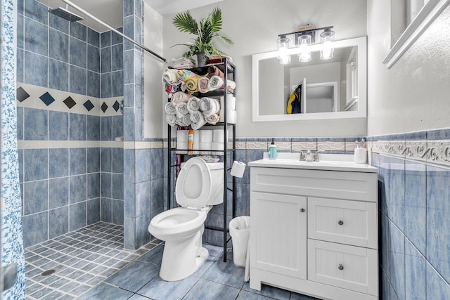 bathroom with tile patterned floors, a stall shower, tile walls, wainscoting, and vanity