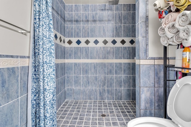 bathroom featuring wainscoting, a stall shower, and tile walls