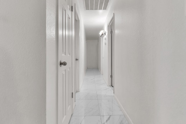 corridor with visible vents, marble finish floor, a textured wall, and baseboards