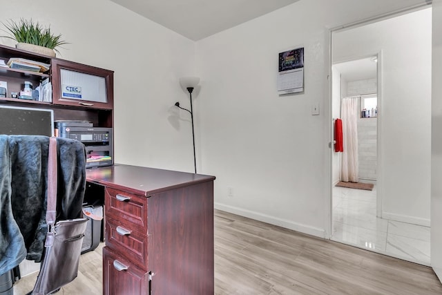 home office with light wood-style flooring and baseboards