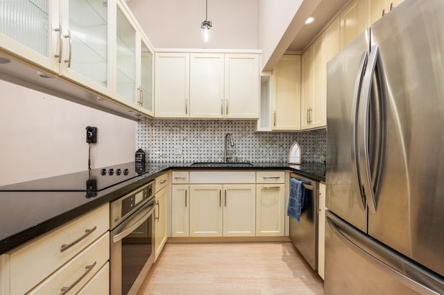 kitchen with tasteful backsplash, sink, stainless steel appliances, light wood-type flooring, and cream cabinetry