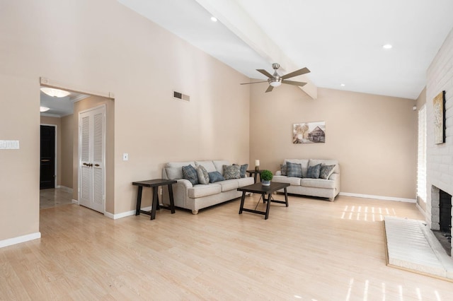 living room with ceiling fan, a fireplace, light hardwood / wood-style flooring, and vaulted ceiling with beams