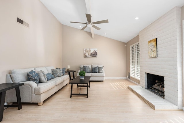 living room featuring ceiling fan, lofted ceiling, light hardwood / wood-style floors, and a brick fireplace