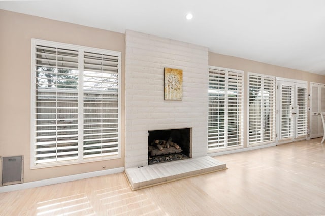 unfurnished living room with wood-type flooring and a brick fireplace