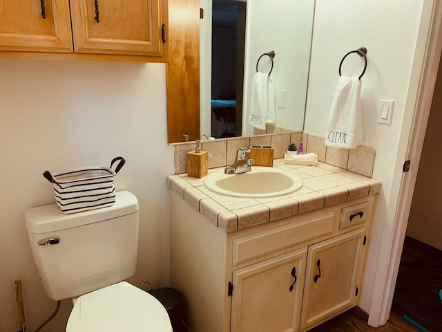 bathroom featuring vanity, decorative backsplash, and toilet