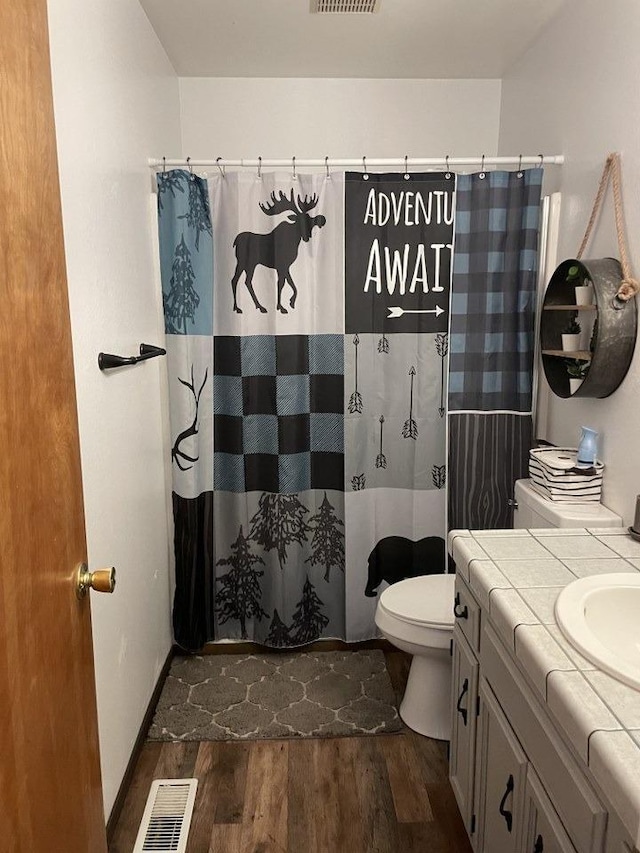 bathroom with wood-type flooring, toilet, curtained shower, and vanity