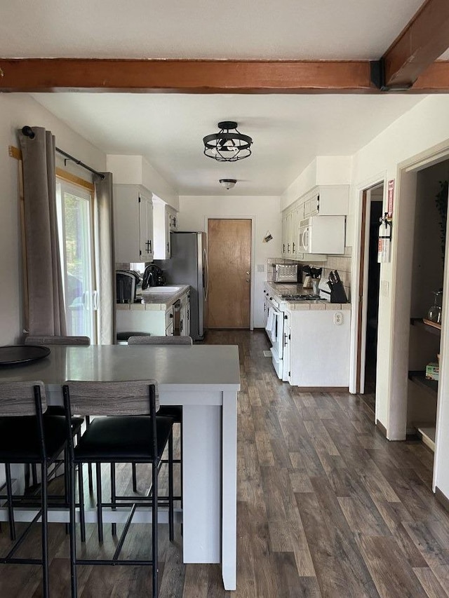 kitchen featuring white cabinetry, backsplash, white appliances, kitchen peninsula, and beam ceiling