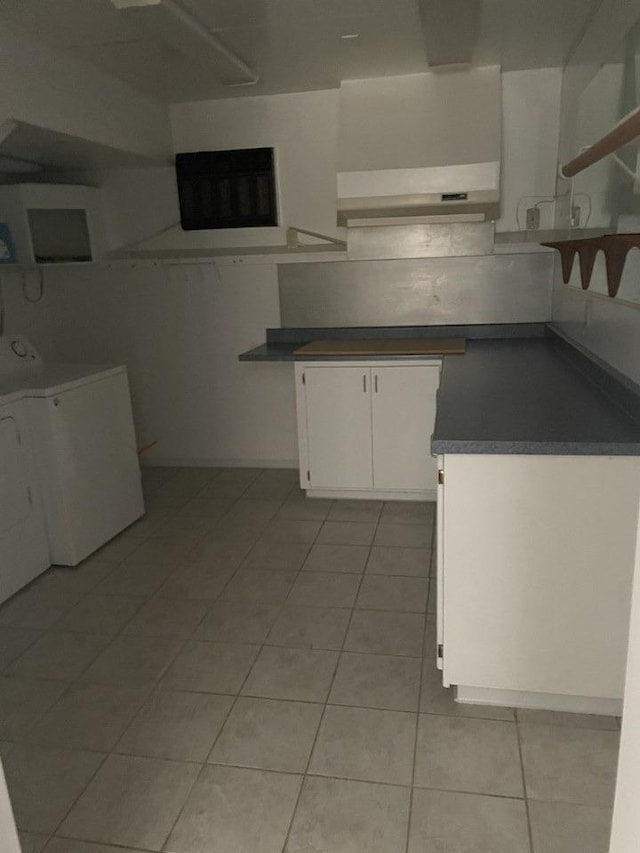 kitchen featuring washer / clothes dryer, light tile patterned floors, and white cabinets