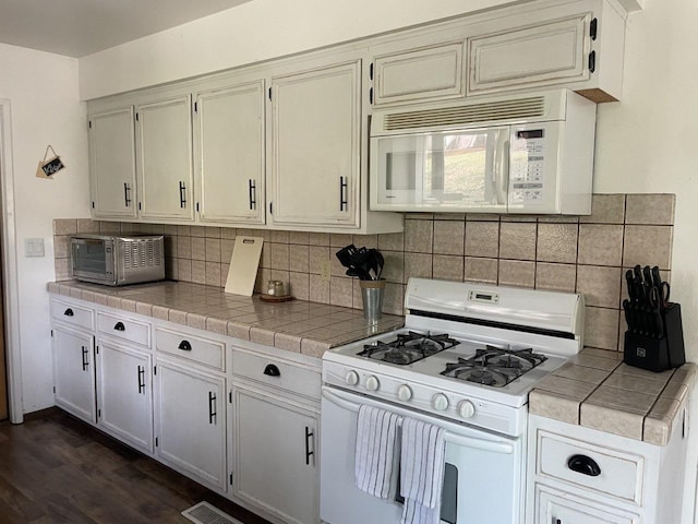 kitchen with dark hardwood / wood-style floors, tile countertops, white appliances, and decorative backsplash