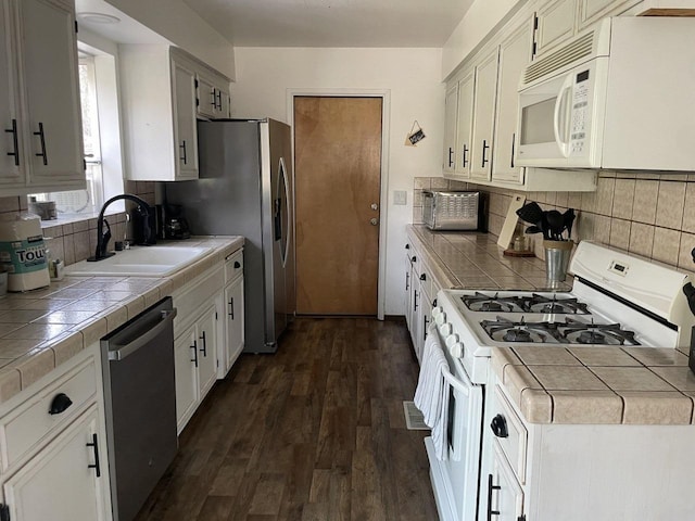 kitchen featuring white cabinetry, appliances with stainless steel finishes, sink, and tile counters