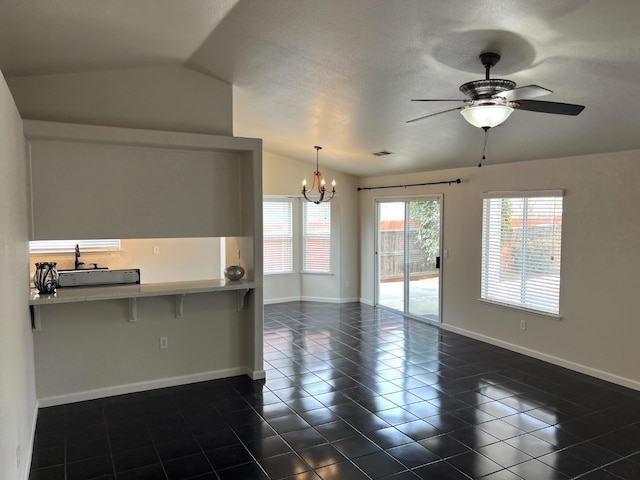 tiled empty room featuring lofted ceiling, ceiling fan with notable chandelier, and a textured ceiling