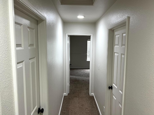 hall with dark colored carpet