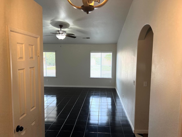 spare room with ceiling fan and dark tile patterned flooring