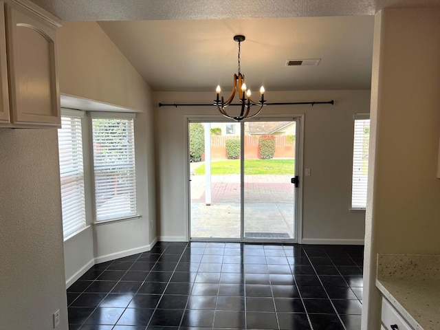 unfurnished dining area featuring dark tile patterned flooring, a chandelier, and a healthy amount of sunlight