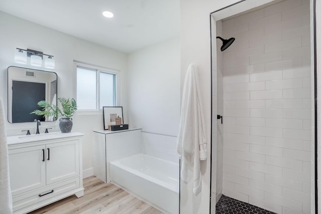 bathroom with wood-type flooring, separate shower and tub, and vanity