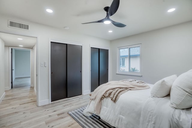 bedroom featuring multiple closets, ceiling fan, and light hardwood / wood-style flooring