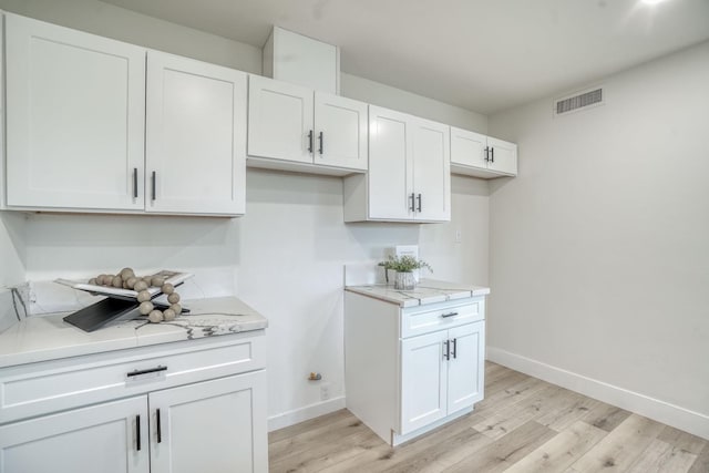 kitchen with light stone countertops, light hardwood / wood-style flooring, and white cabinets